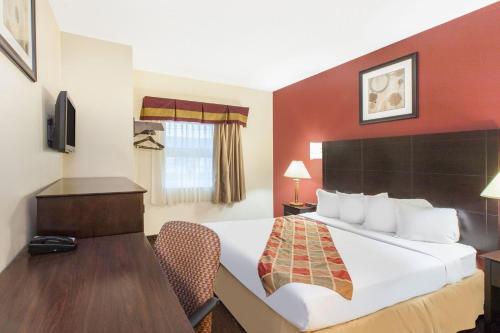 a hotel room with a bed and a desk at Travelodge by Wyndham Romulus Detroit Airport in Romulus