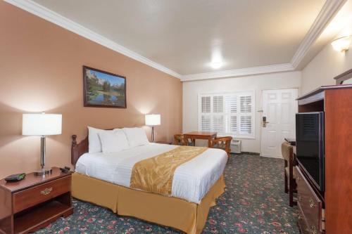 a hotel room with a bed and a flat screen tv at Days Inn & Suites by Wyndham South Gate in South Gate