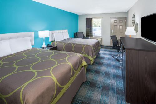 a hotel room with two beds and a flat screen tv at Howard Johnson by Wyndham Vicksburg in Vicksburg