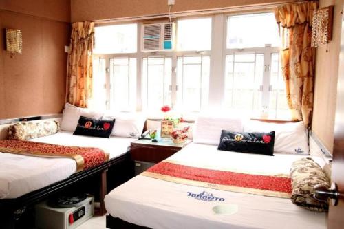 two beds in a room with a window at New Fortunate Guest House in Hong Kong