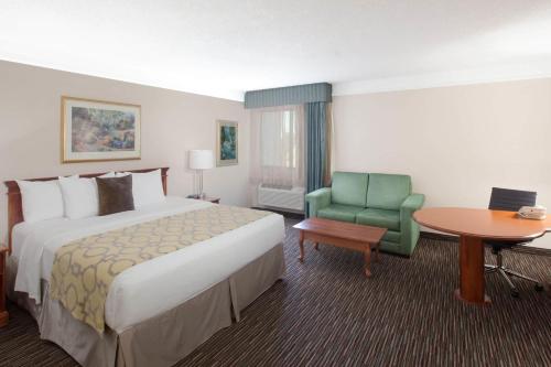 a hotel room with a large bed and a green chair at Baymont by Wyndham Texarkana in Texarkana