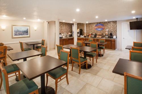 a restaurant with tables and chairs and a kitchen at Baymont by Wyndham Texarkana in Texarkana
