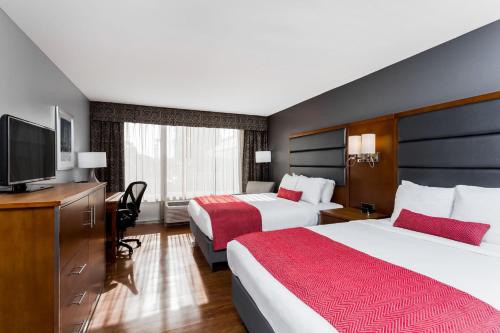 a hotel room with two beds and a flat screen tv at Wyndham Garden Greensboro in Greensboro