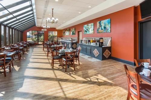 a dining room with tables and chairs and a bar at Wyndham Garden Greensboro in Greensboro