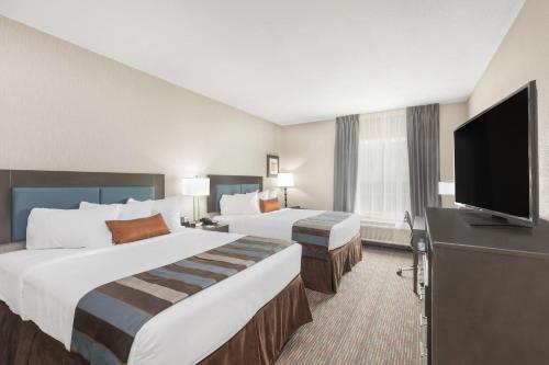 a hotel room with two beds and a flat screen tv at Wingate by Wyndham Lubbock in Lubbock