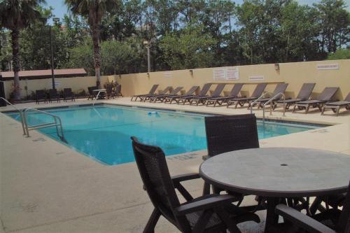 a pool with chairs and a table in front of it at Wyndham Garden Hotel - Jacksonville in Jacksonville