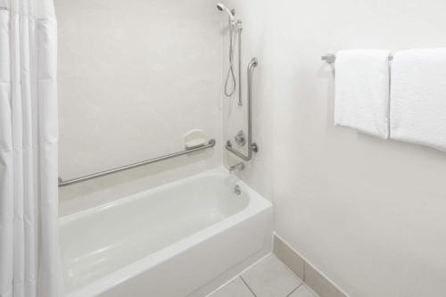 a white bathroom with a bath tub and towels at Wingate by Wyndham Shreveport Airport in Shreveport