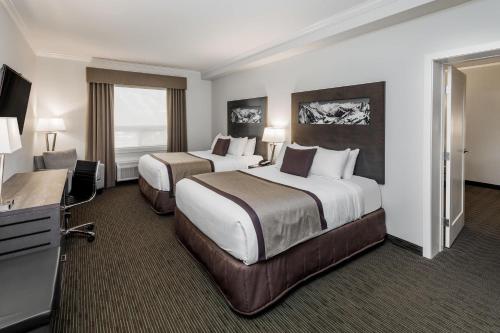 a hotel room with two beds and a television at Ramada by Wyndham Revelstoke in Revelstoke