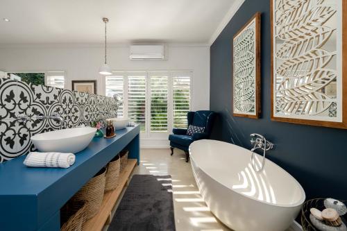 a bathroom with two sinks and a bath tub at Long Story Guest House in Plettenberg Bay