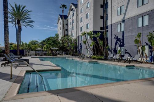 a swimming pool in a hotel with chairs and palm trees at Homewood Suites by Hilton-Anaheim in Anaheim