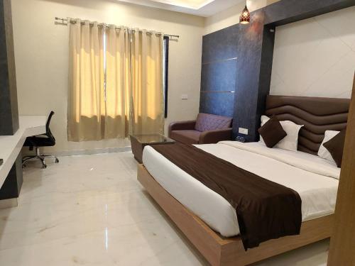 a bedroom with a large bed and a desk at Hotel Sunny Jhalawar in Jhālāwār