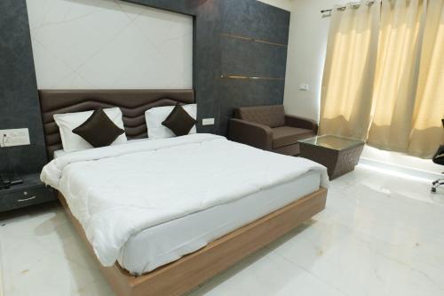 a bedroom with a large bed and a chair at Hotel Sunny Jhalawar in Jhālāwār