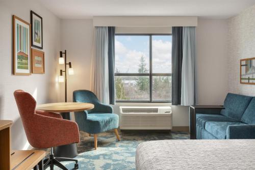 a hotel room with a bed and a table and chairs at Hampton Inn & Suites by Hilton Langley-Surrey in Surrey