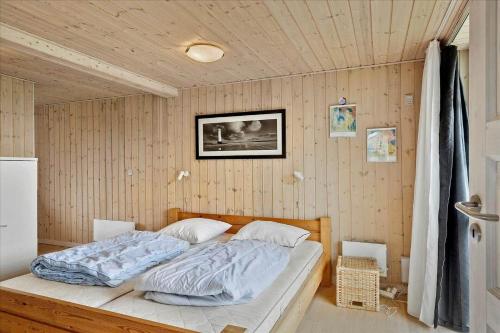 a bed in a bedroom with a wooden wall at 20145-Ulfborg-Knakvej-16 in Ulfborg