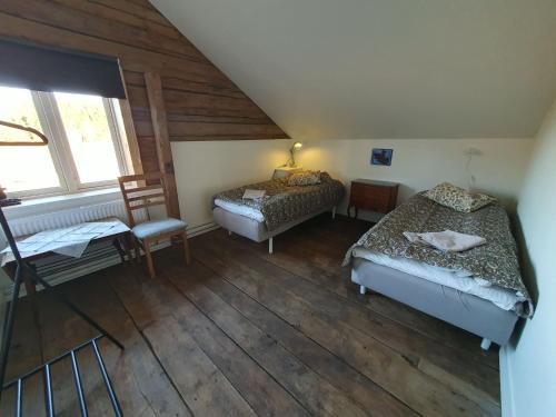 a attic room with two beds and a chair at Magasinet Stora Långbro in Tystberga
