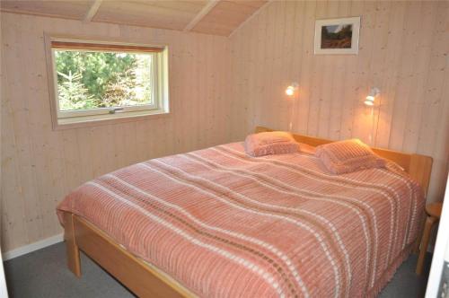 a bedroom with a bed with a striped comforter and a window at 30070-Ulfborg-Klovervej-478 in Ulfborg