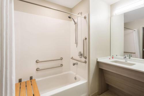 a bathroom with a white tub and a sink at Microtel Inn & Suites by Wyndham Springville in Springville