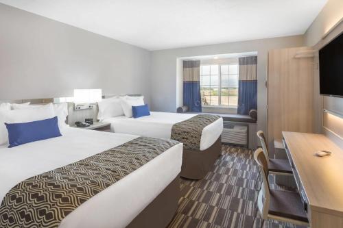 a hotel room with two beds and a flat screen tv at Microtel Inn & Suites by Wyndham Springville in Springville
