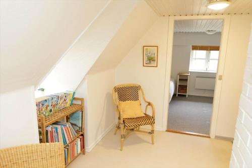 a room with a chair and a book shelf with books at 10294-Ulfborg-Gaffelbjergvej-44 in Ulfborg