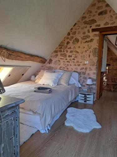 a bedroom with a bed and a stone wall at Maison la Bambine chambre nature in Ozolles