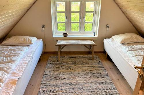 two beds in a room with a table and a window at 20708-Ulfborg-Sortebaervej-6 in Ulfborg