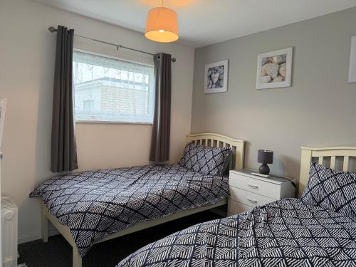 a bedroom with two beds and a window at 62 M&T Chalets , 2 bed detached chalet Florida holiday park Hemsby in Hemsby