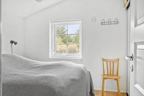 a bedroom with a bed and a chair and a window at 10808-Ulfborg-Vester-Mosevej-84 in Ulfborg