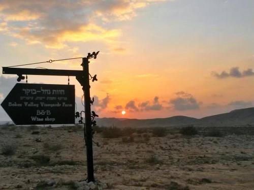 a sign in the desert with the sunset in the background at Boker Valley Farm in Sede Boqer