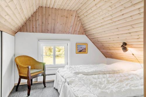 a bedroom with a bed and a chair and a window at 10718-Ulfborg-Baekbyvej-117 in Ulfborg