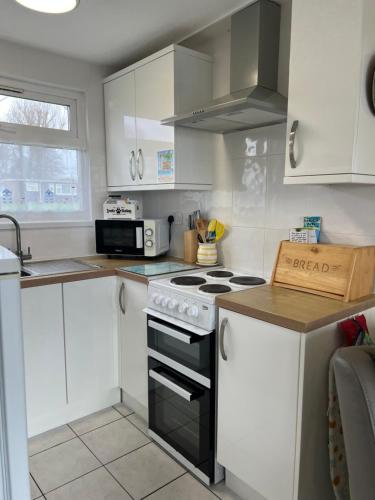a kitchen with white cabinets and a stove top oven at 'Sunnyside' Chalet, walk to the beach & close to Norfolk broads - pet friendly! in Great Yarmouth