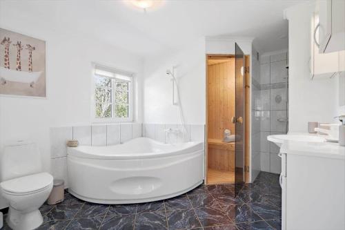 a white bathroom with a tub and a toilet at 10833-Ulfborg-Graemvej-19 in Ulfborg