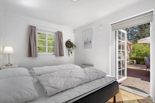 a white bedroom with a large bed and a window at 10833-Ulfborg-Graemvej-19 in Ulfborg