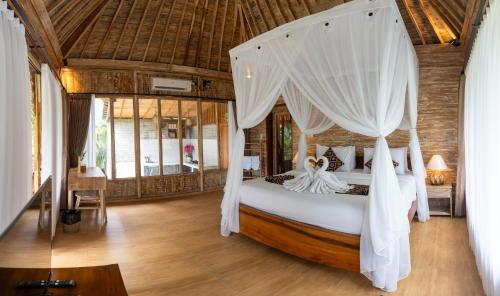 a bedroom with a bed with a canopy at The Fire Flies Garden Villa in Penginyahan