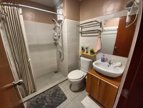 a bathroom with a toilet and a sink and a shower at Jade's Place Condo in Bacolod