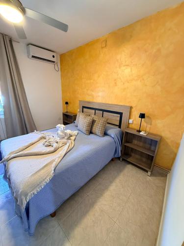 a bedroom with a blue bed and a yellow wall at Casa Pumba in San Martín de la Vega