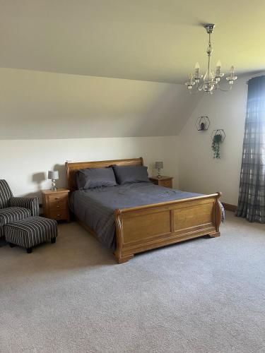 a bedroom with a bed and a chair and a chandelier at Ardbrae Apartments in Daviot