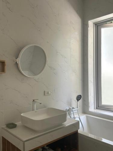 a white bathroom with a sink and a mirror at Villa Colette in Ban Hua Laem Ma So