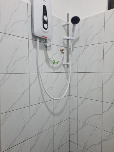 a shower with a hose on a white wall at Mutodon Green in Kuala Penyu