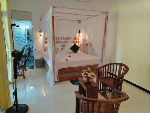 a bedroom with a bed with a mosquito net at Robert Ayurveda Villa in Bentota
