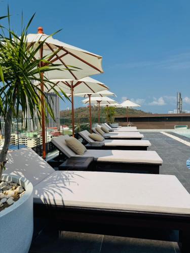 a row of lounge chairs with umbrellas on a roof at Samsara Hotel Pattaya in Pattaya South