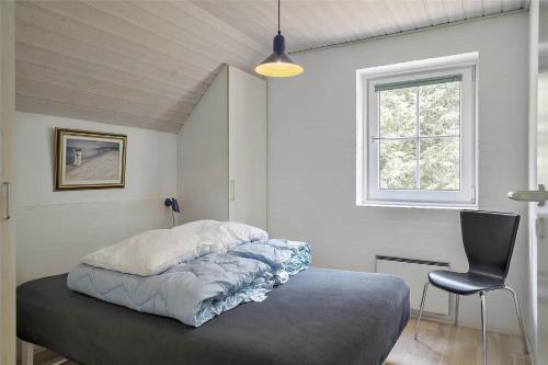 a bedroom with a bed with a chair and a window at 10607-Ulfborg-Gaffelbjergvej-38 in Ulfborg