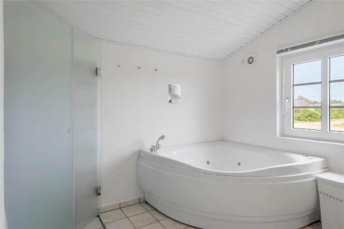 a white bathroom with a tub and a window at 20733-Ulfborg-Sortebaervej-4 in Ulfborg