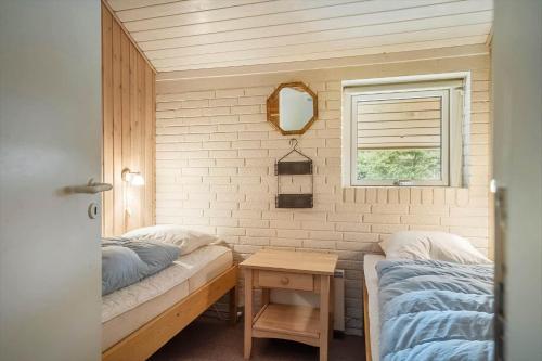 a bedroom with two beds and a table and a window at 30705-Ulfborg-Valmuevej-288 in Ulfborg