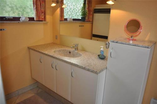 a bathroom with a sink and a mirror and a refrigerator at 30061-Ulfborg-Kaprifolievej-6 in Ulfborg