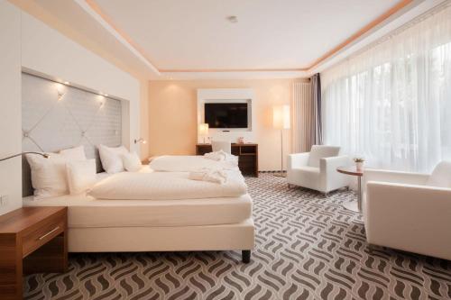 a hotel room with a large white bed and a desk at Moin Hotel Cuxhaven in Cuxhaven
