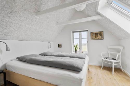 a white bedroom with a bed and a chair at 70222-Ulfborg-Jagtvejen-8 in Ulfborg