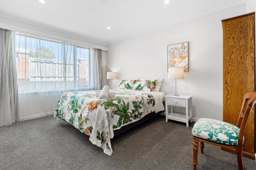 a bedroom with a bed and a window and a chair at Roslyn Sanctuary Highgate Dunedin in Dunedin