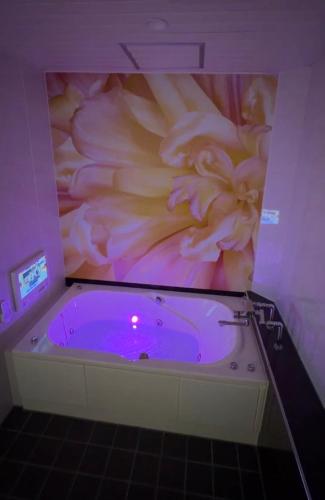 a bath tub with a large flower painting on the wall at ホテルパルシス大人専用 in Shiroishi