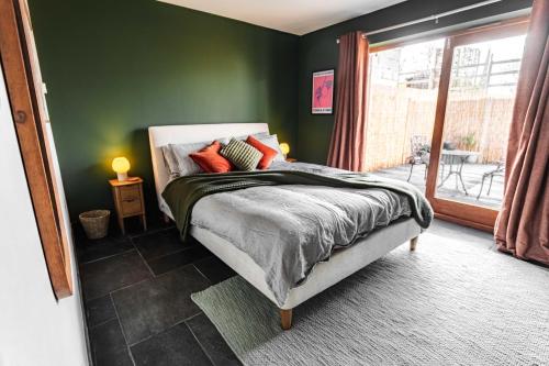 a bedroom with green walls and a bed with red pillows at New House Barn in Ashbourne