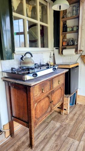 a kitchen with a stove top on a wooden island at Treguth Glamping Unique Experience - Themed Huts in Saint Day